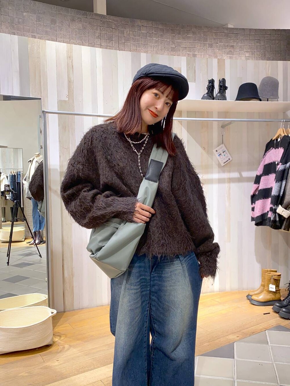 グリーン系のボディバッグ/ウエストポーチ、ブルー系のデニムパンツ、ブラウン系のニット/セーターを着用したレディースの秋コーディネートの3枚目の写真