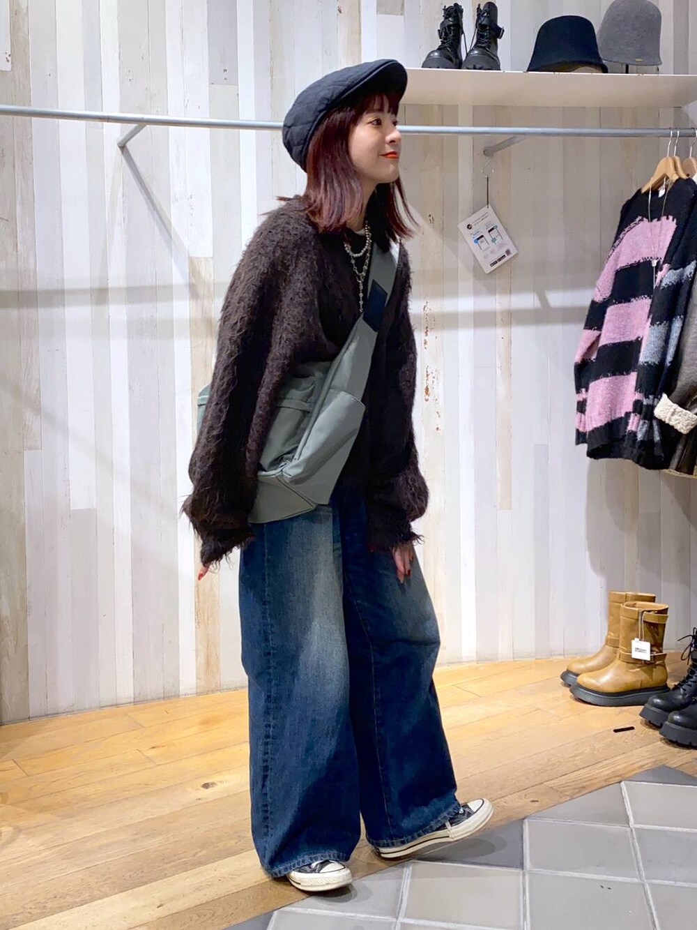 グリーン系のボディバッグ/ウエストポーチ、ブルー系のデニムパンツ、ブラウン系のニット/セーターを着用したレディースの秋コーディネートの2枚目の写真