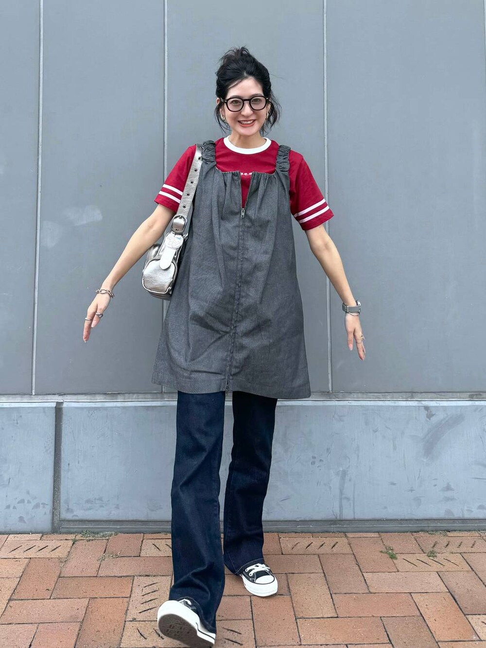 シルバー系のショルダーバッグ、レッド系のTシャツ/カットソー、グレー系のジャンパースカートを着用したレディースの夏コーディネートの7枚目の写真