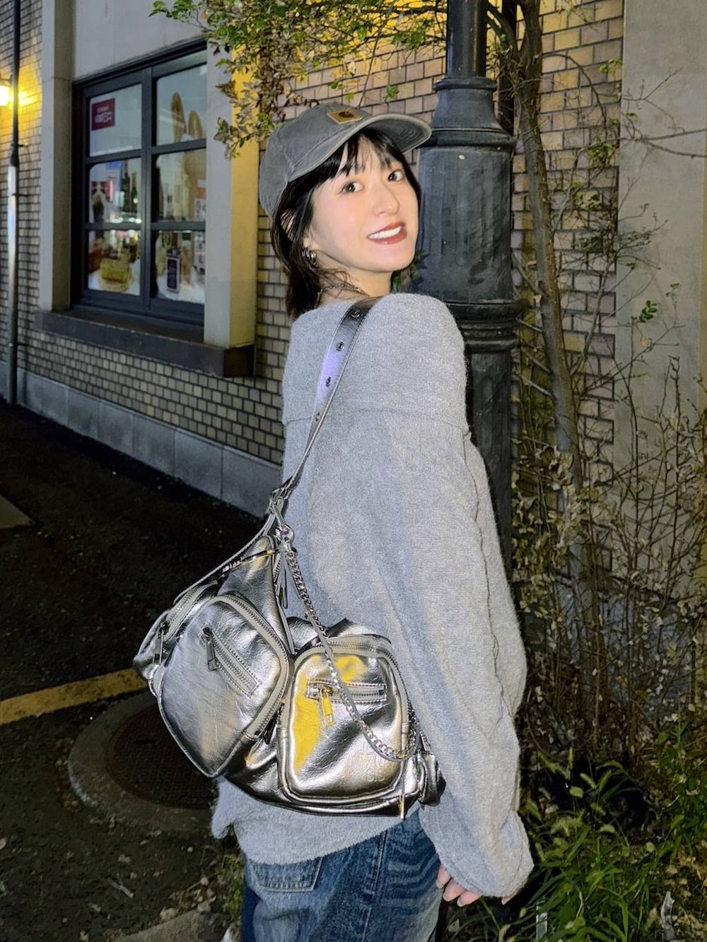 シルバー系のショルダーバッグ、ブルー系のデニムパンツ、グレー系のTシャツ/カットソーを着用したレディースの秋コーディネートの3枚目の写真