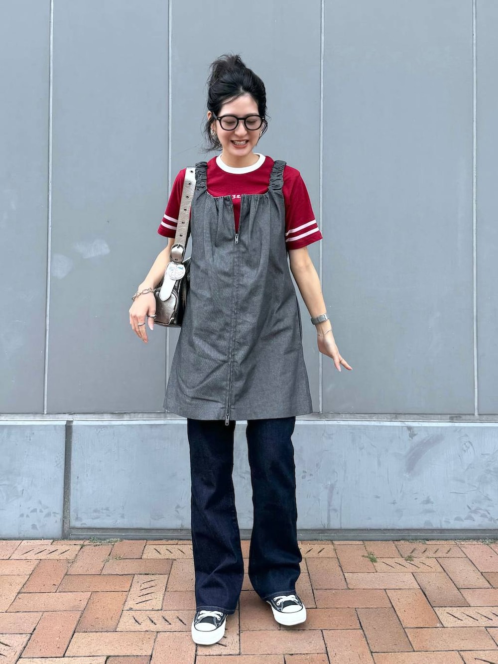 シルバー系のショルダーバッグ、レッド系のTシャツ/カットソー、グレー系のジャンパースカートを着用したレディースの夏コーディネートの2枚目の写真