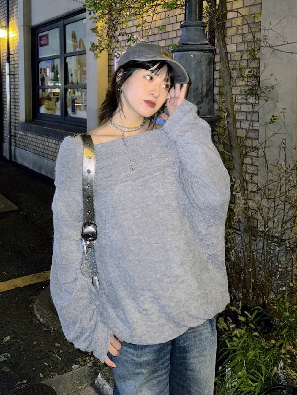 シルバー系のショルダーバッグ、ブルー系のデニムパンツ、グレー系のTシャツ/カットソーを着用したレディースの秋コーディネートの2枚目の写真