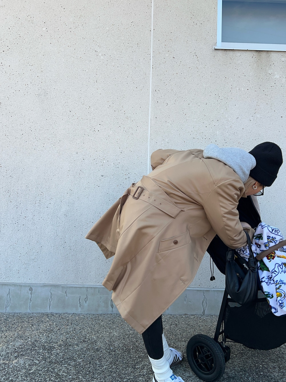 ベージュ系のトレンチコート、ブラック系のバッグ、ホワイト系のスニーカーを着用したレディースの冬コーディネートの3枚目の写真