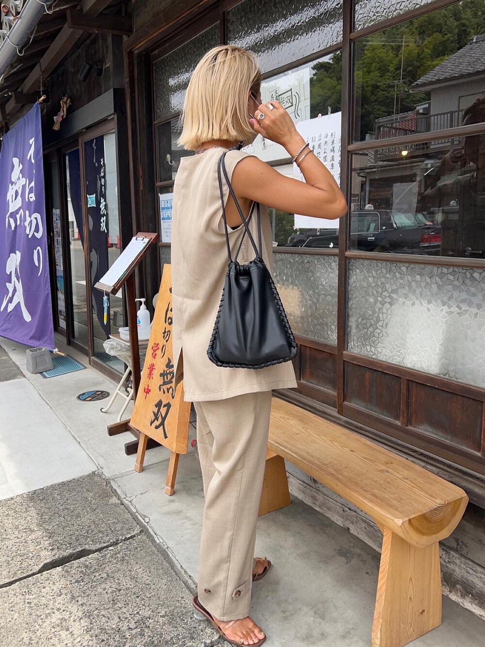 ベージュ系のベスト、ブラック系のショルダーバッグ、ベージュ系のパンツを着用したレディースの夏コーディネートの5枚目の写真