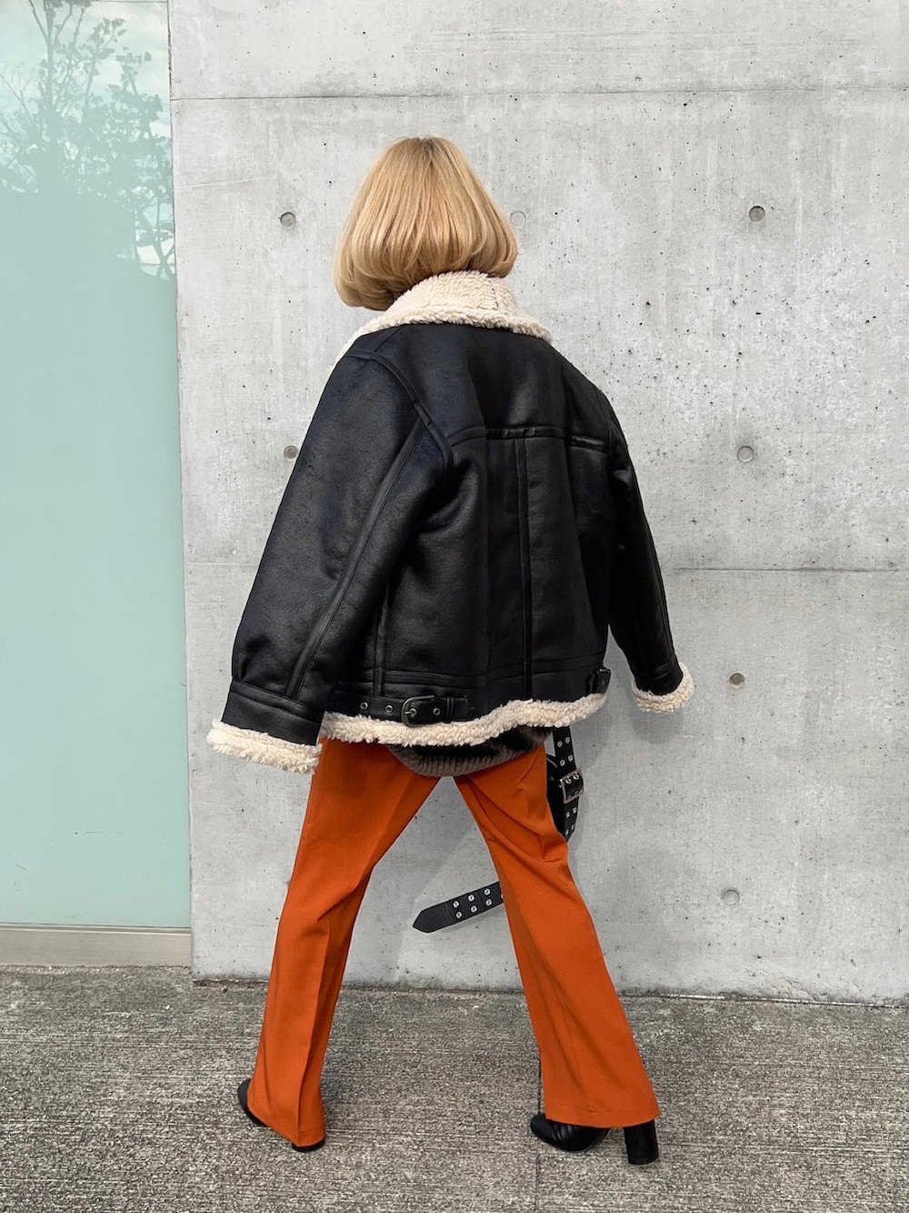 オレンジ系のスラックス、ブラック系のブーツ、グレー系のニット/セーターを着用したレディースの冬コーディネートの5枚目の写真