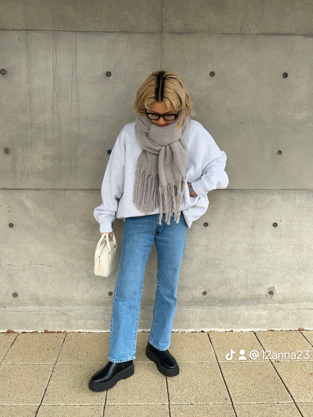 グレー系のスウェット、ブラック系のブーツ、ブルー系のデニムパンツを着用したレディースの冬コーディネートの3枚目の写真