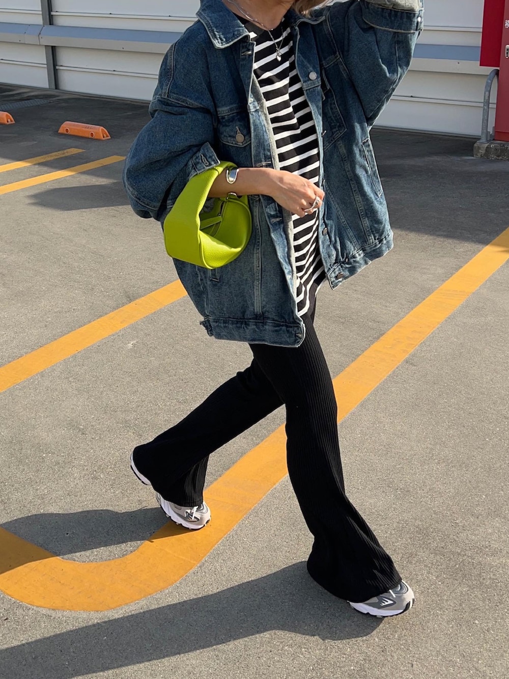 ブラック系のパンツ、グレー系のスニーカー、グリーン系のショルダーバッグを着用したレディースの春コーディネートの3枚目の写真