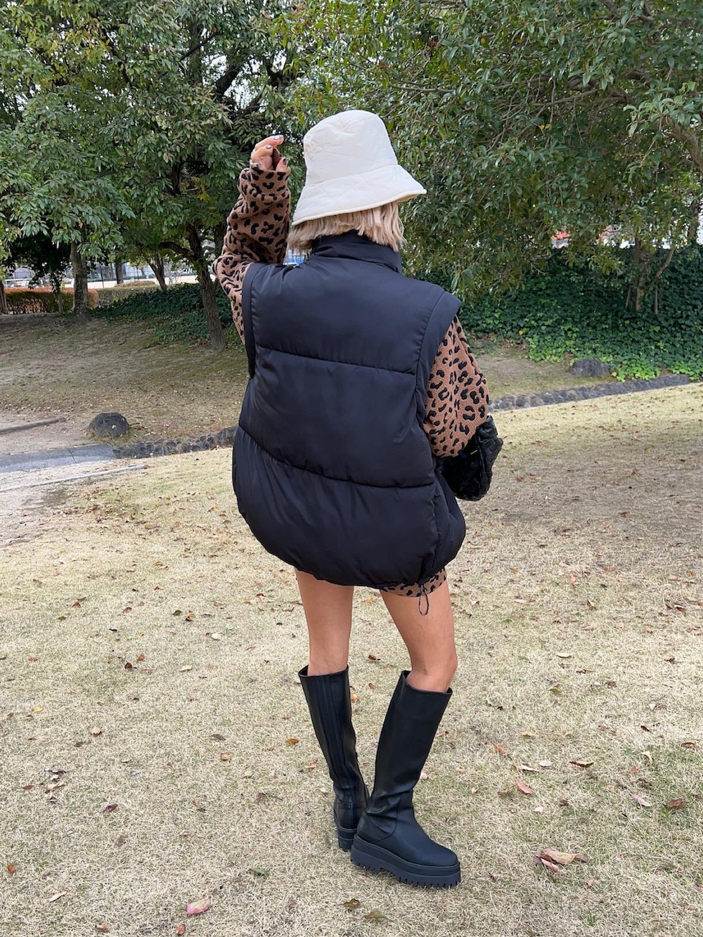 ブラック系のブーツ、ブラック系のハンドバッグ、ブラック系のベストを着用したレディースの冬コーディネートの3枚目の写真