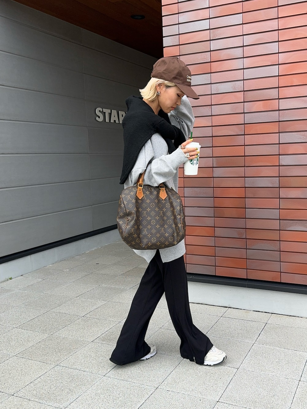 グレー系のTシャツ/カットソー、ブラック系のニット/セーター、ベージュ系のスニーカーを着用したレディースの秋コーディネートの3枚目の写真