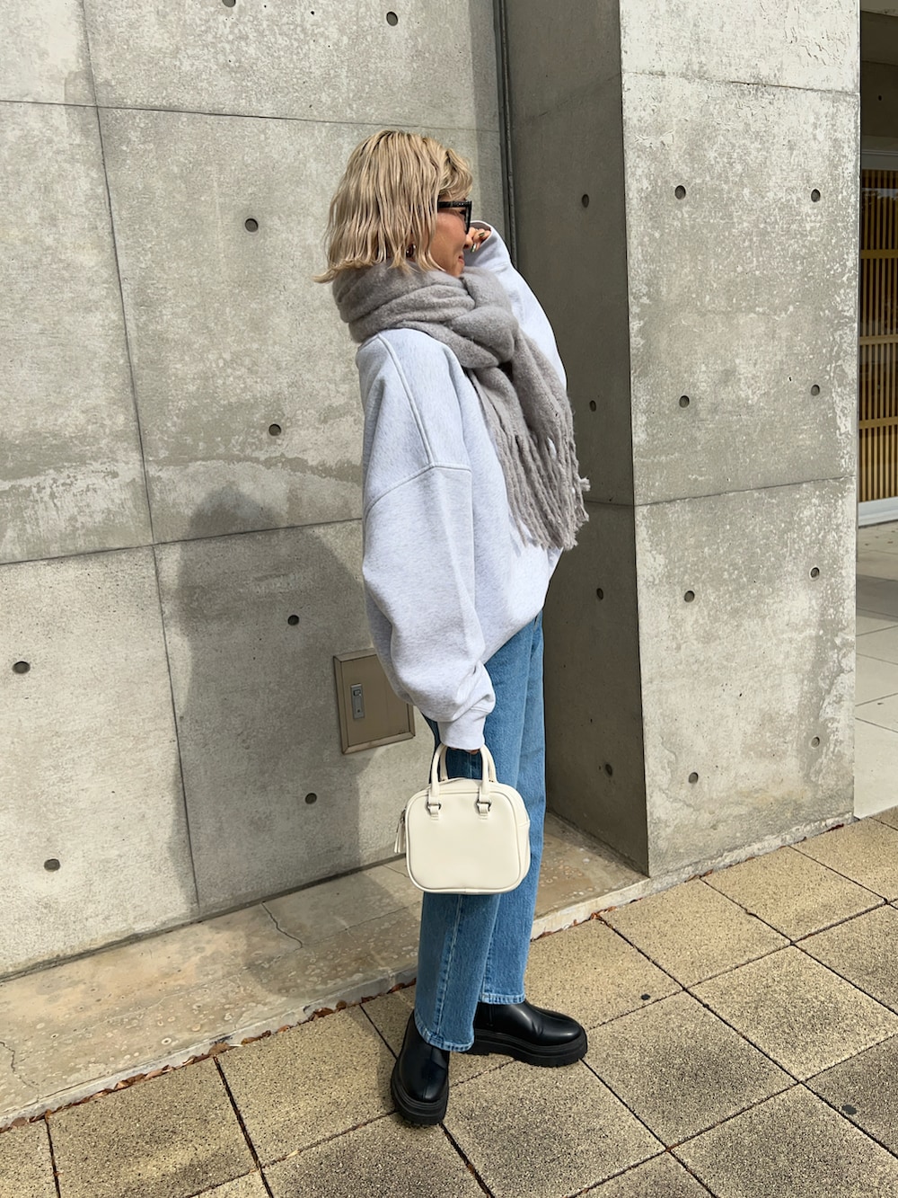 グレー系のスウェット、ブラック系のブーツ、ブルー系のデニムパンツを着用したレディースの冬コーディネートの2枚目の写真