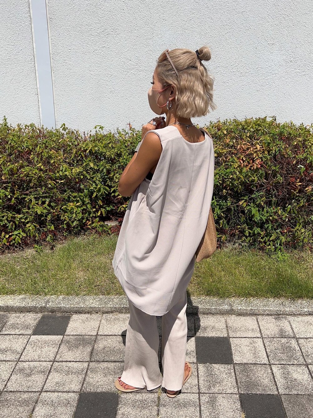 ベージュ系のベスト、イエロー系のトートバッグ、ホワイト系のタンクトップを着用したレディースの夏コーディネートの2枚目の写真