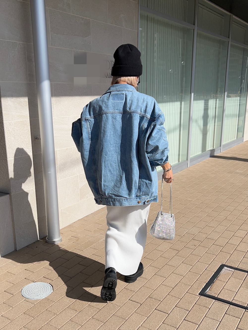 ホワイト系のスカート、ブラック系のブーツ、シルバー系のショルダーバッグを着用したレディースの冬コーディネートの2枚目の写真