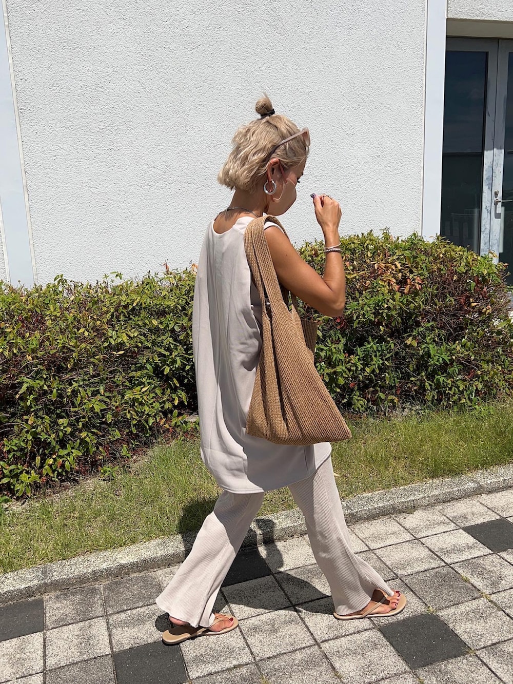 ベージュ系のベスト、イエロー系のトートバッグ、ホワイト系のタンクトップを着用したレディースの夏コーディネートの3枚目の写真