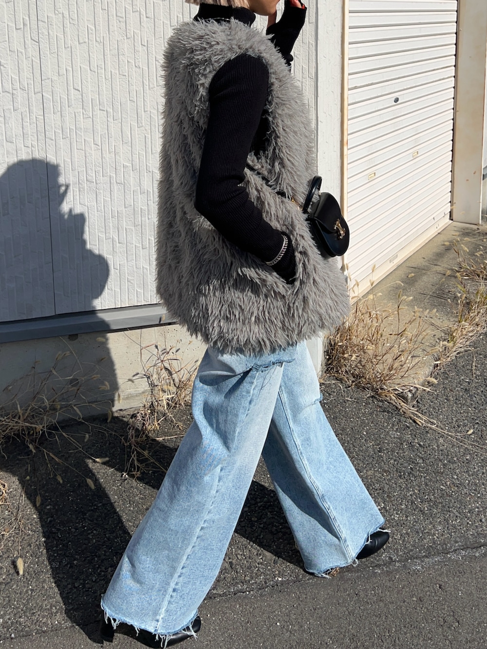 グレー系のベスト、ブルー系のデニムパンツ、ブラック系のブーツを着用したレディースの冬コーディネートの3枚目の写真