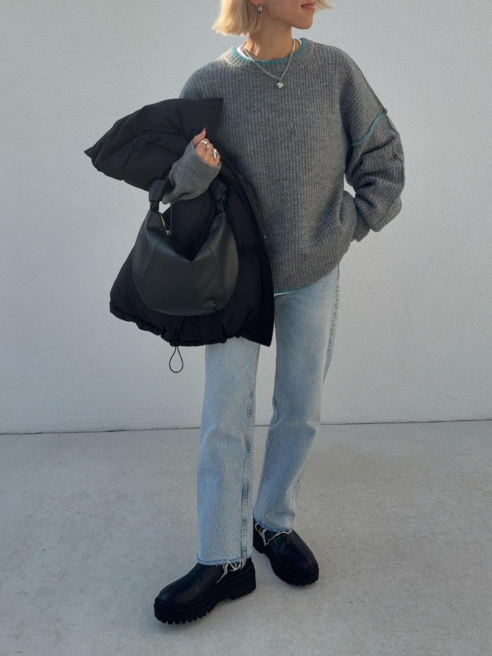 ブルー系のデニムパンツ、グレー系のニット/セーター、ブラック系のハンドバッグを着用したレディースの秋コーディネートの5枚目の写真