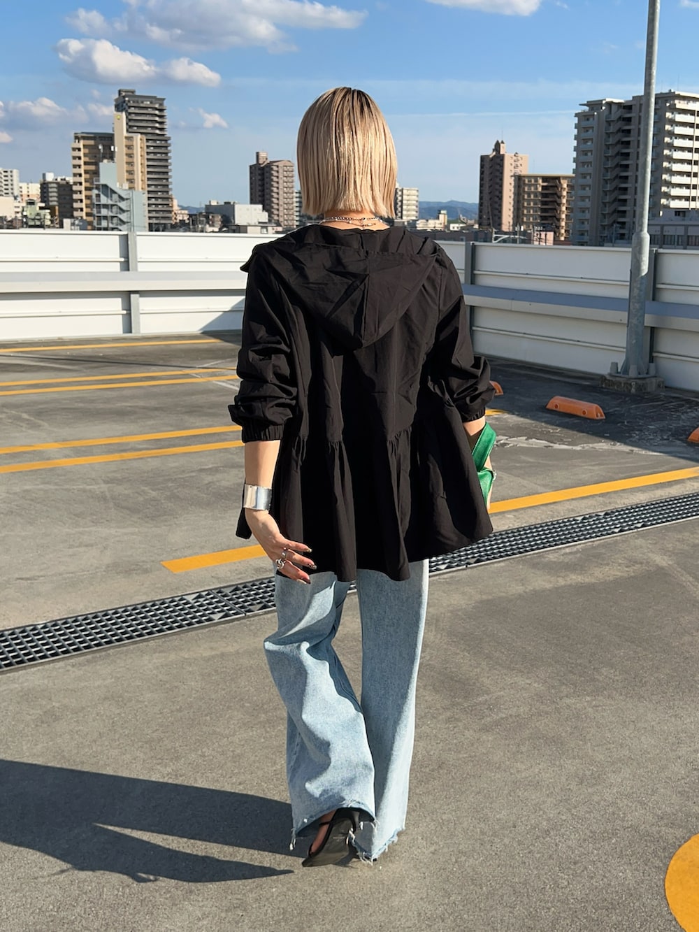 ブルー系のデニムパンツ、ブラック系のサンダル、グリーン系のショルダーバッグを着用したレディースの春コーディネートの2枚目の写真