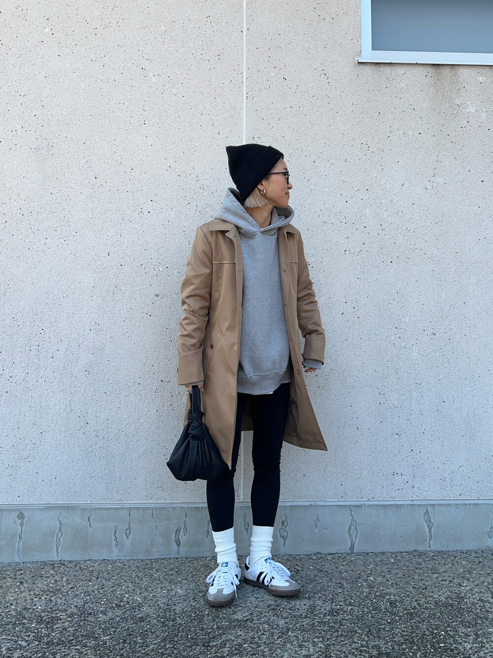 ベージュ系のトレンチコート、ブラック系のバッグ、ホワイト系のスニーカーを着用したレディースの冬コーディネートの4枚目の写真