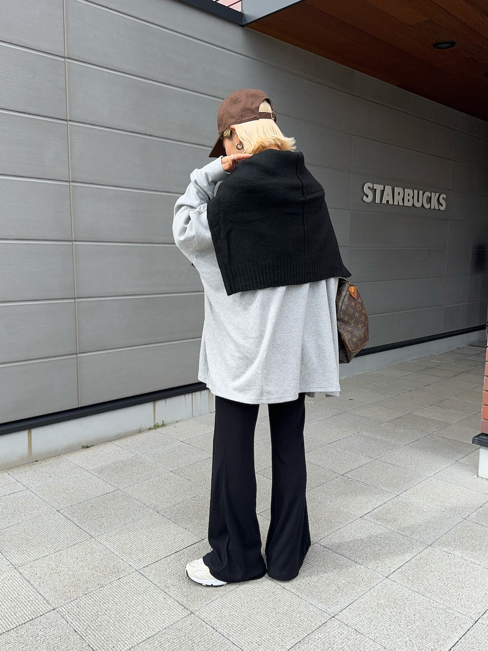 グレー系のTシャツ/カットソー、ブラック系のニット/セーター、ベージュ系のスニーカーを着用したレディースの秋コーディネートの2枚目の写真