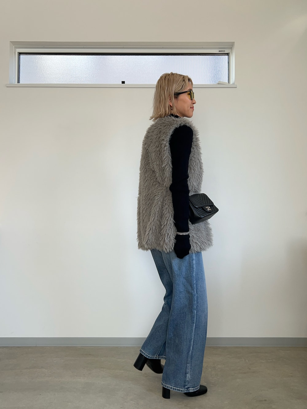 グレー系のベスト、ブルー系のデニムパンツ、ブラック系のブーツを着用したレディースの冬コーディネートの3枚目の写真