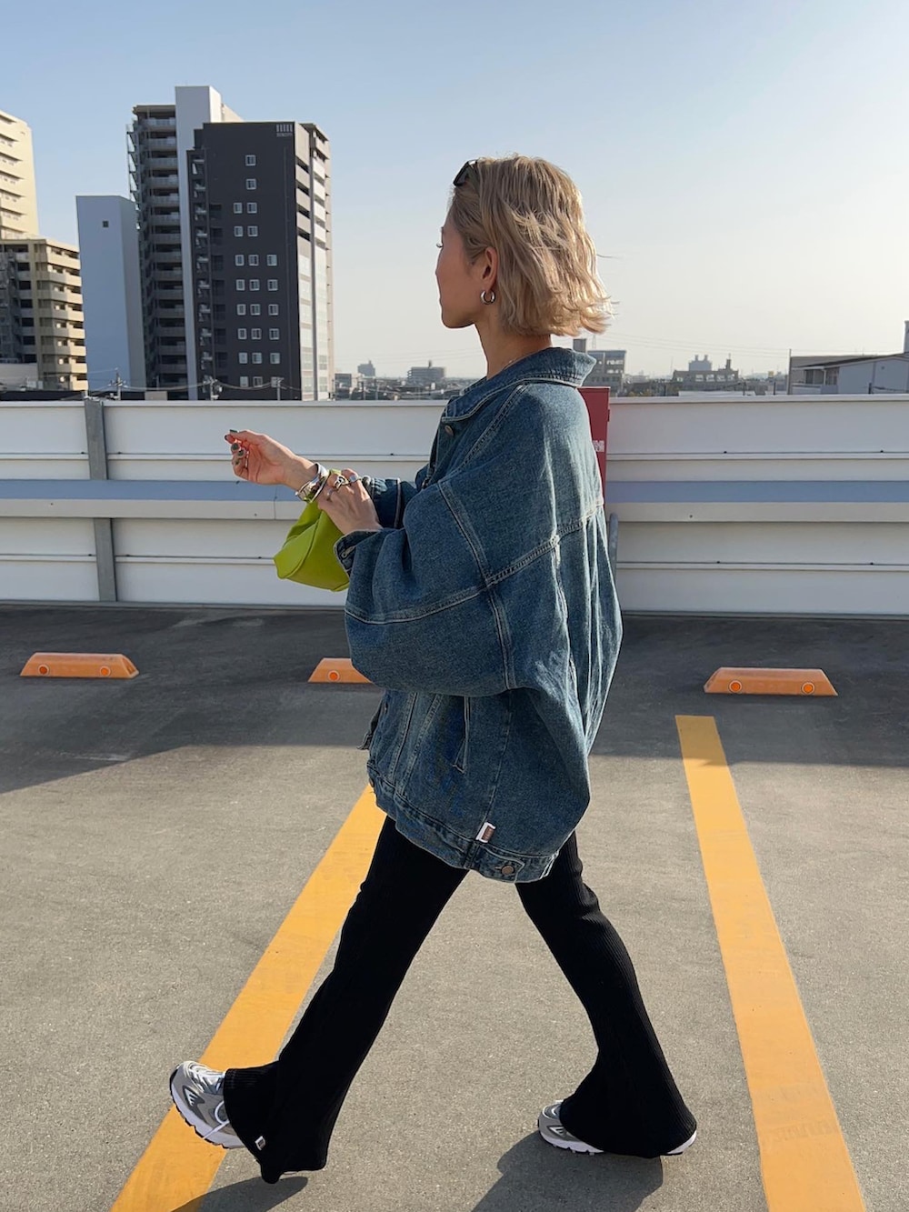 ブラック系のパンツ、グレー系のスニーカー、グリーン系のショルダーバッグを着用したレディースの春コーディネートの2枚目の写真