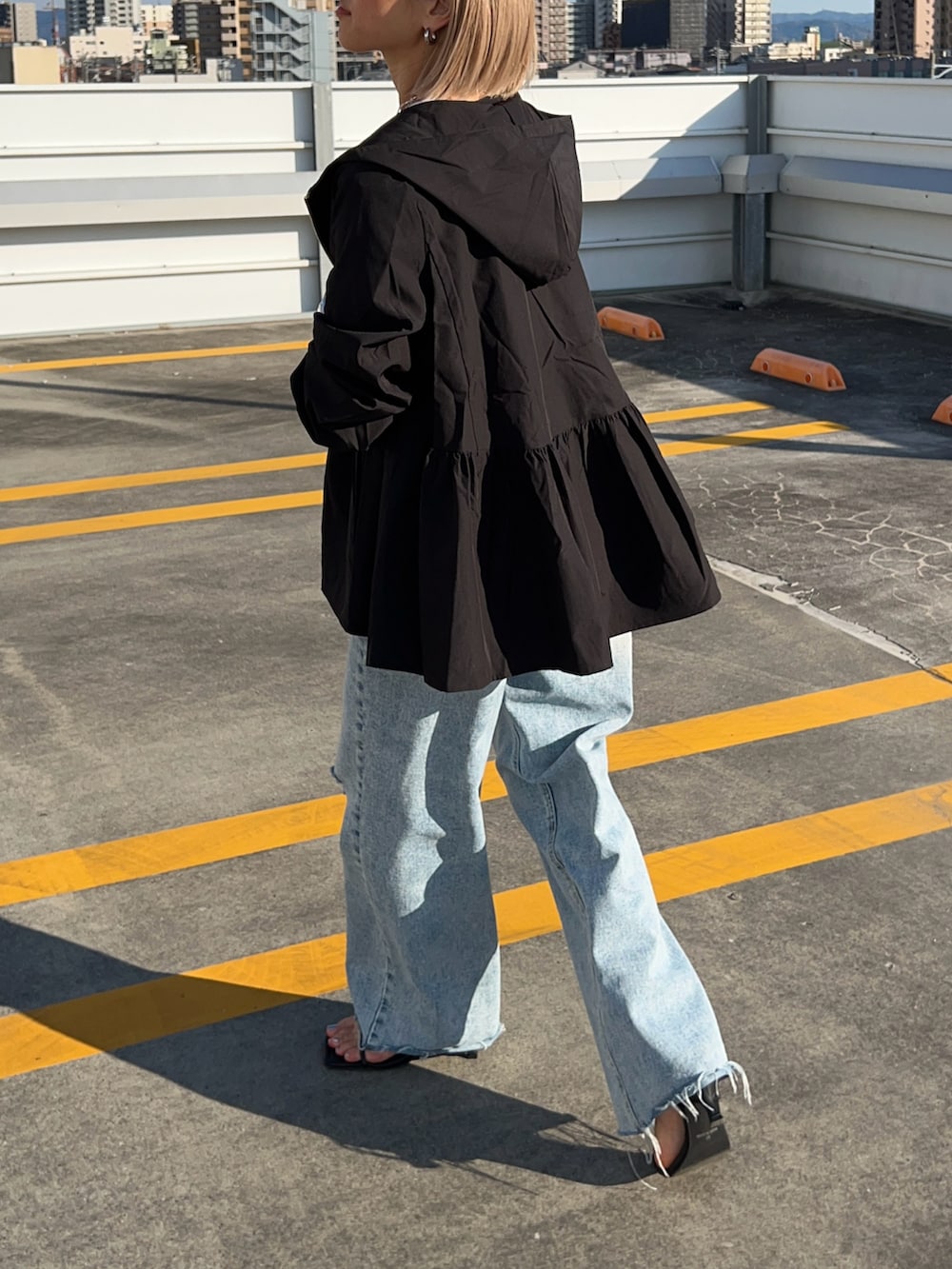 ブルー系のデニムパンツ、ブラック系のサンダル、グリーン系のショルダーバッグを着用したレディースの春コーディネートの3枚目の写真