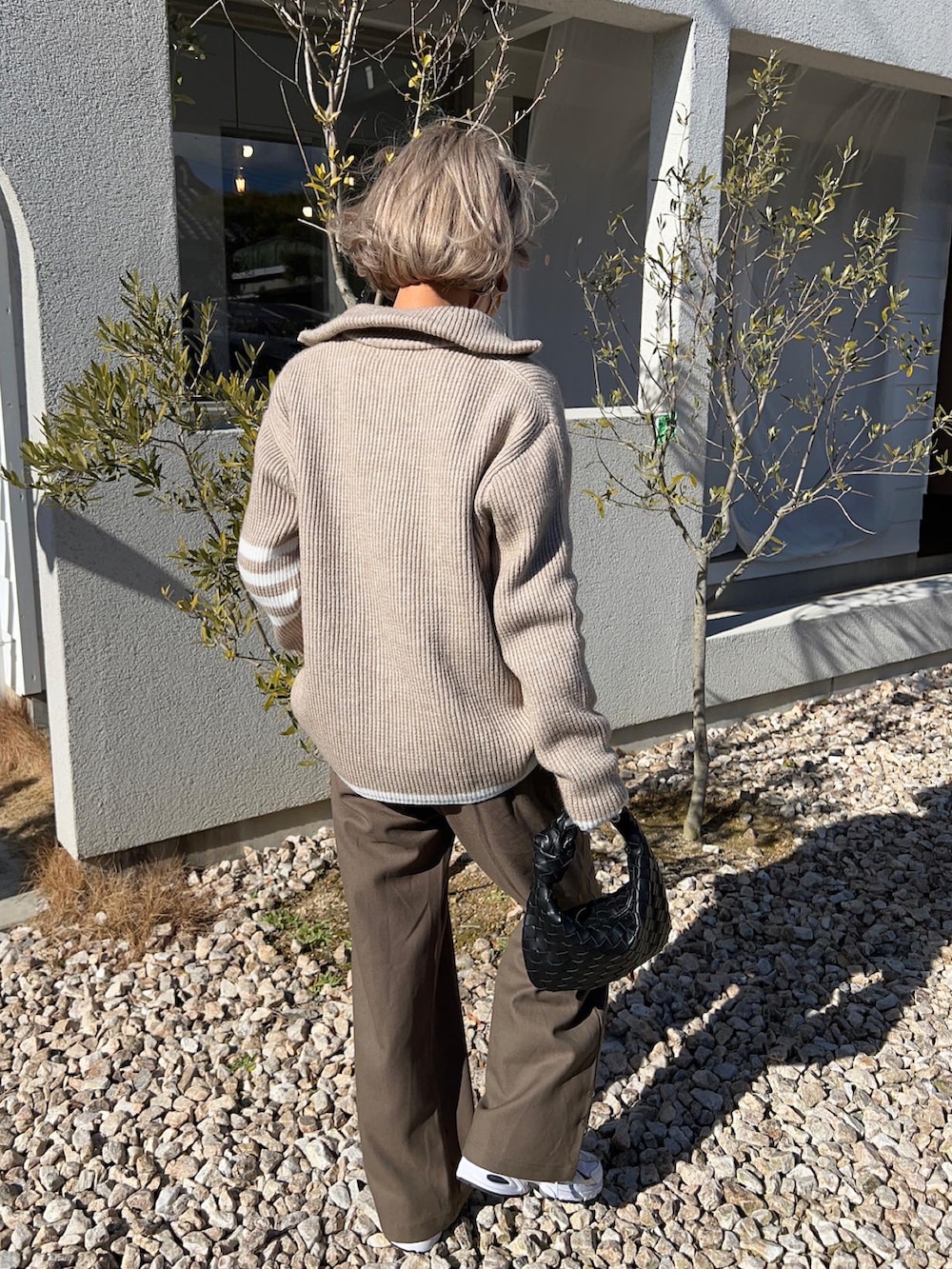 ホワイト系のスニーカー、ブラック系のハンドバッグ、ベージュ系のニット/セーターを着用したレディースの冬コーディネートの5枚目の写真