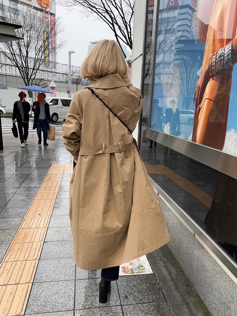 ベージュ系のトレンチコート、ブラック系のブーツ、ブルー系のデニムパンツを着用したレディースの春コーディネートの4枚目の写真