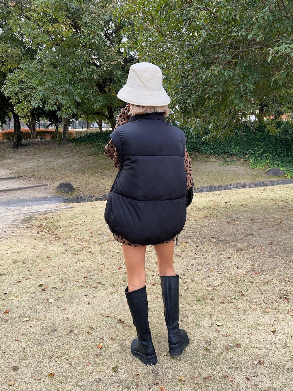 ブラック系のブーツ、ブラック系のハンドバッグ、ブラック系のベストを着用したレディースの冬コーディネートの5枚目の写真