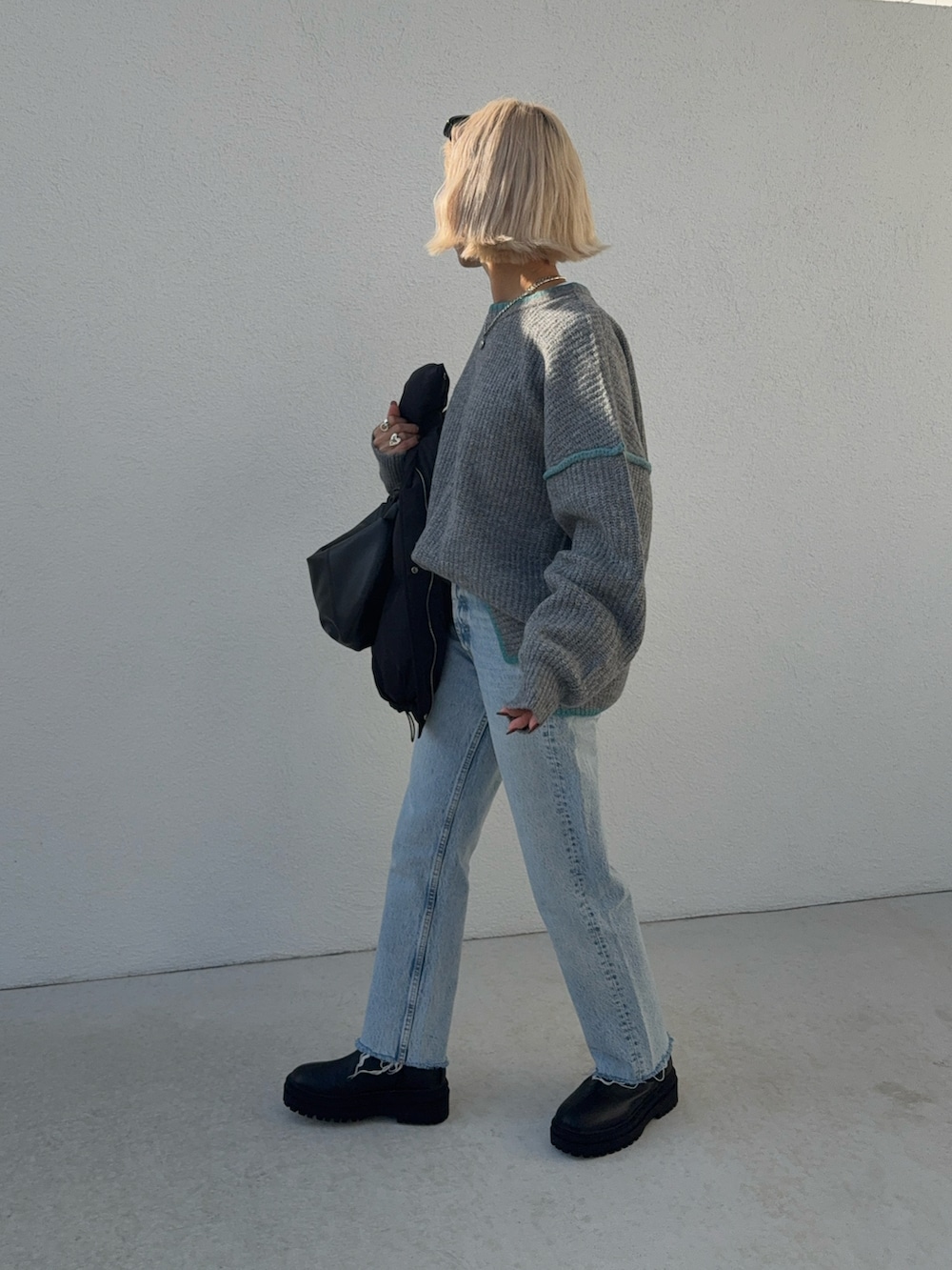 ブルー系のデニムパンツ、グレー系のニット/セーター、ブラック系のハンドバッグを着用したレディースの秋コーディネートの4枚目の写真