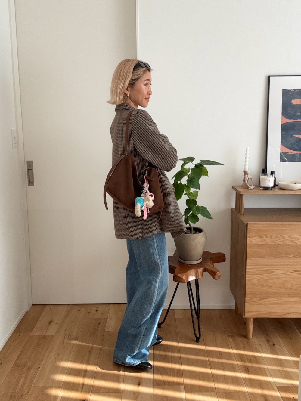 ブラウン系のテーラードジャケット、ブラウン系のショルダーバッグ、ブルー系のデニムパンツを着用したレディースの冬コーディネートの2枚目の写真