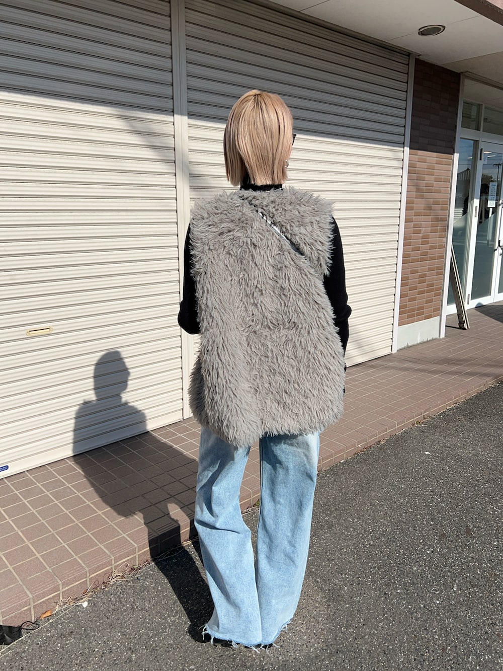 グレー系のベスト、ブルー系のデニムパンツ、ブラック系のブーツを着用したレディースの冬コーディネートの4枚目の写真