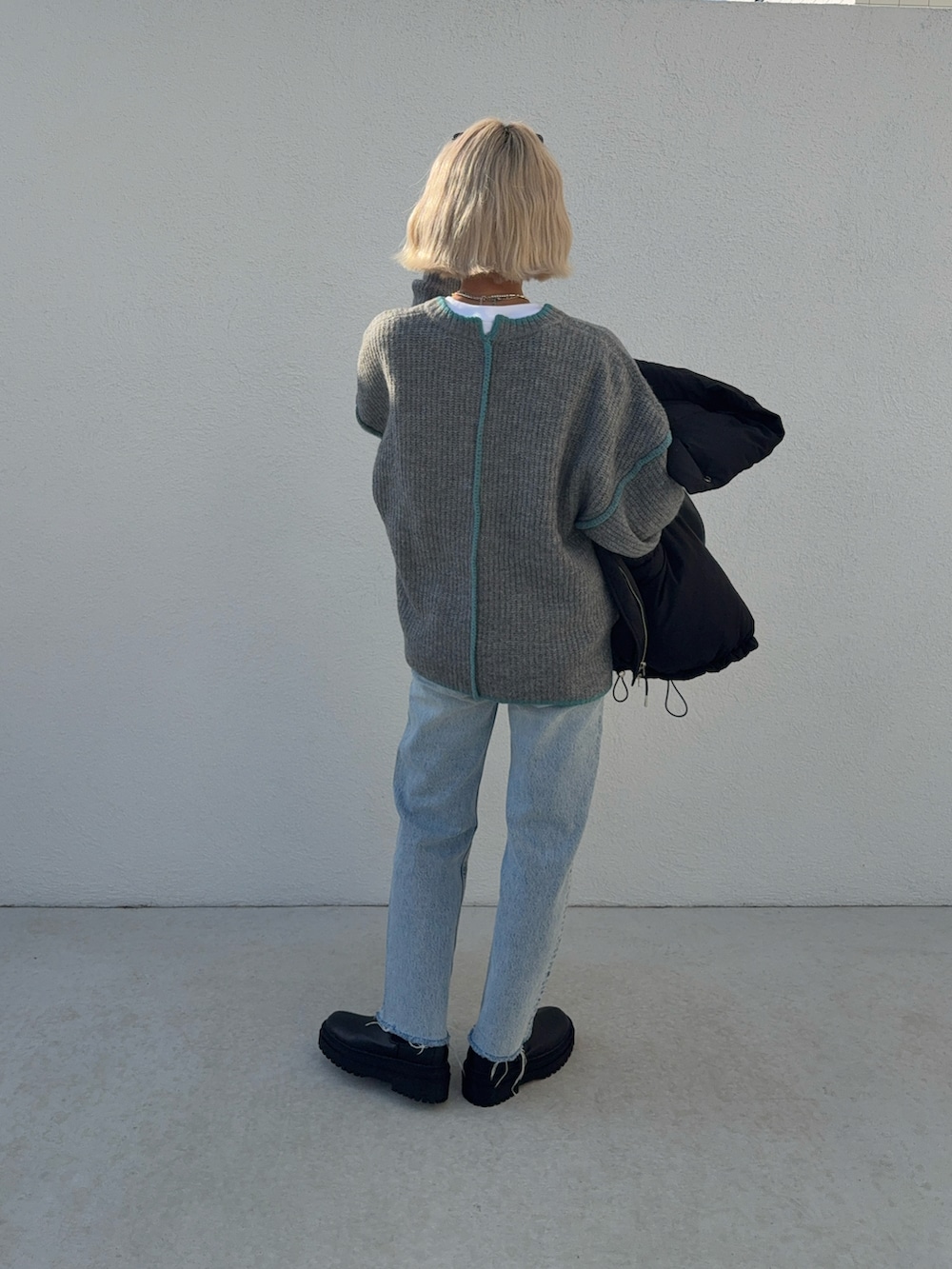 ブルー系のデニムパンツ、グレー系のニット/セーター、ブラック系のハンドバッグを着用したレディースの秋コーディネートの3枚目の写真