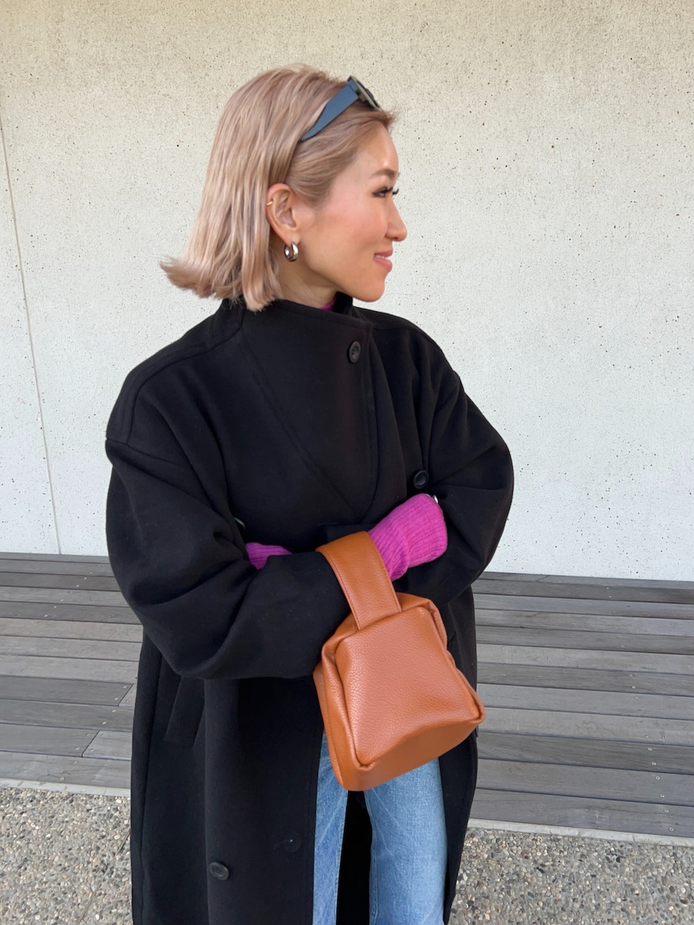 ブラック系のその他アウター、ピンク系のニット/セーター、ブルー系のデニムパンツを着用したレディースの秋コーディネートの4枚目の写真