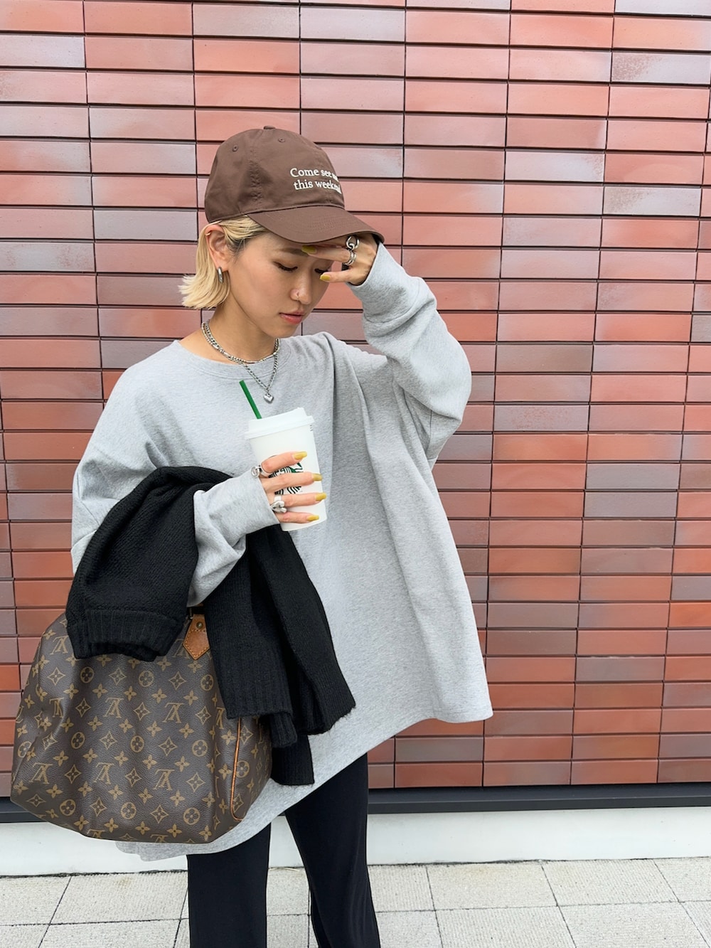 グレー系のTシャツ/カットソー、ブラック系のニット/セーター、ベージュ系のスニーカーを着用したレディースの秋コーディネートの5枚目の写真