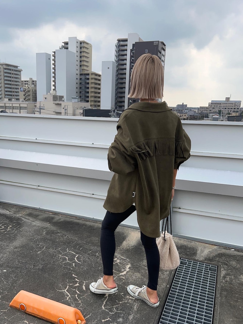 グリーン系のミリタリージャケット、ベージュ系のバッグを着用したレディースの秋コーディネートの2枚目の写真