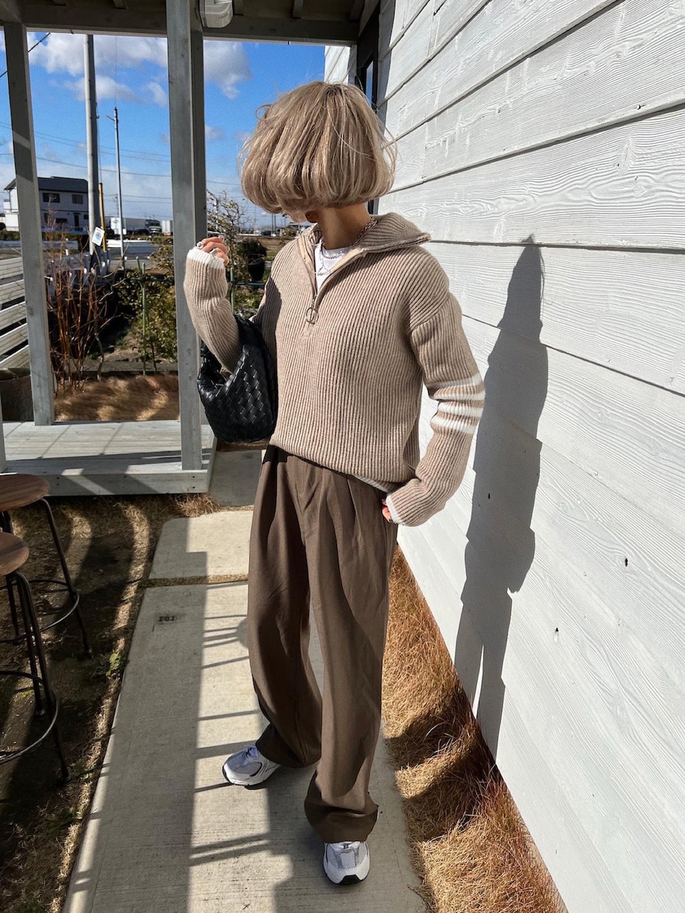 ホワイト系のスニーカー、ブラック系のハンドバッグ、ベージュ系のニット/セーターを着用したレディースの冬コーディネートの3枚目の写真