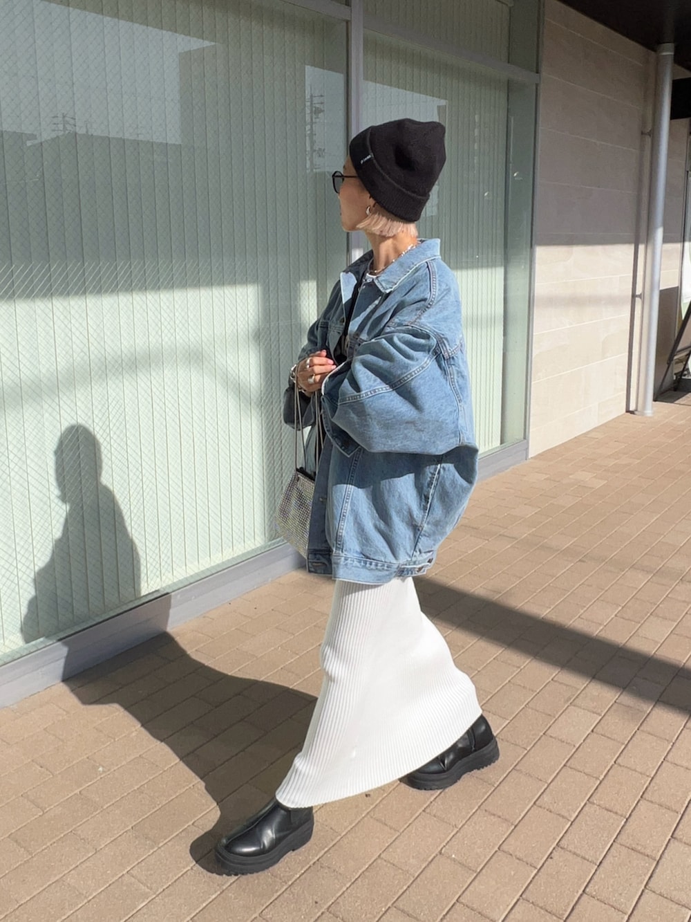 ホワイト系のスカート、ブラック系のブーツ、シルバー系のショルダーバッグを着用したレディースの冬コーディネートの3枚目の写真