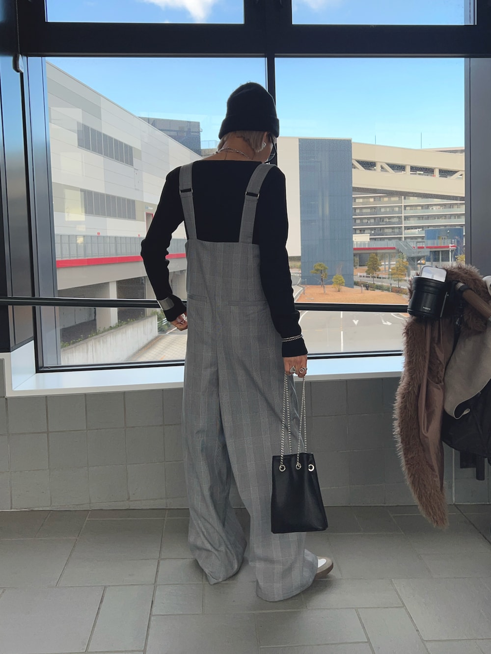 グレー系のサロペット/オーバーオール、ブラック系のニット/セーター、ブラック系のハンドバッグを着用したレディースの冬コーディネートの3枚目の写真