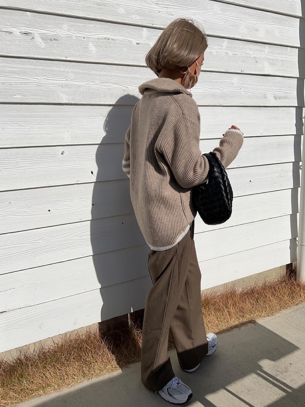 ホワイト系のスニーカー、ブラック系のハンドバッグ、ベージュ系のニット/セーターを着用したレディースの冬コーディネートの4枚目の写真