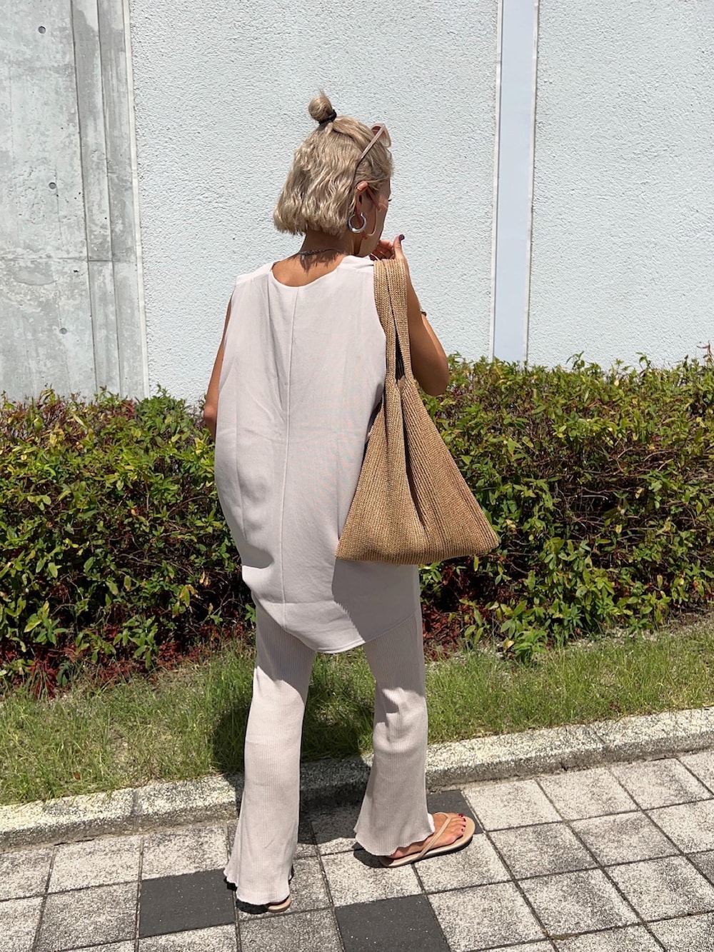 ベージュ系のベスト、イエロー系のトートバッグ、ホワイト系のタンクトップを着用したレディースの夏コーディネートの5枚目の写真