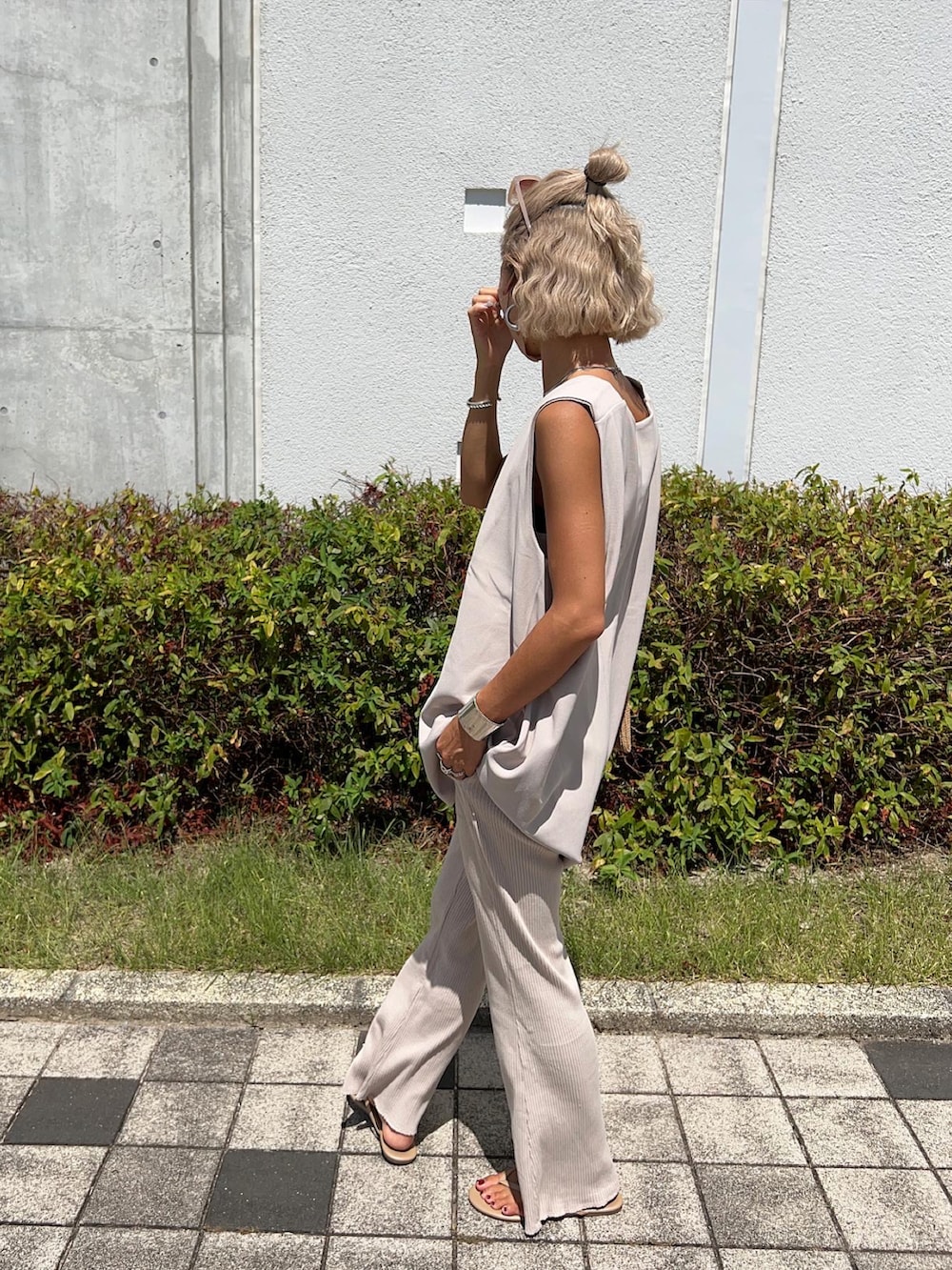 ベージュ系のベスト、イエロー系のトートバッグ、ホワイト系のタンクトップを着用したレディースの夏コーディネートの4枚目の写真