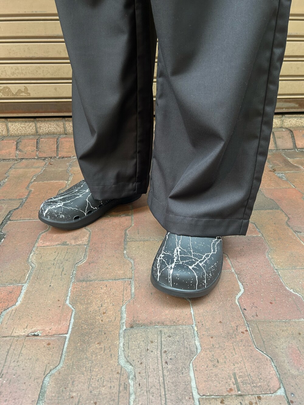 ブラック系のチノパンツ、ブラック系のサンダル、ホワイト系のTシャツ/カットソーを着用したメンズの秋コーディネートの4枚目の写真