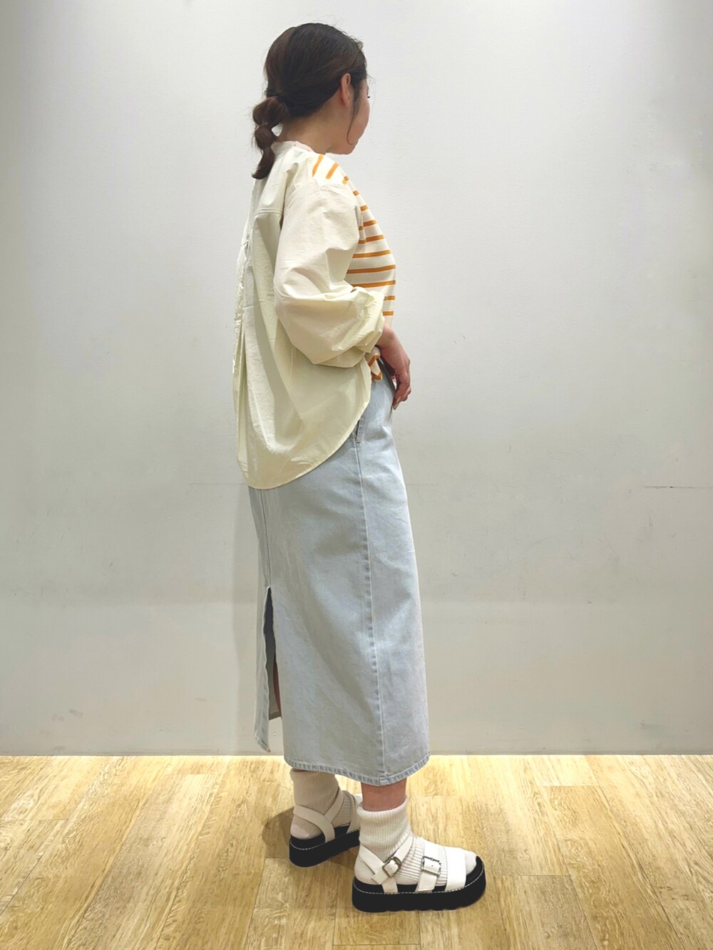 イエロー系のTシャツ/カットソー、ブルー系のスカートを着用したレディースの冬コーディネートの3枚目の写真