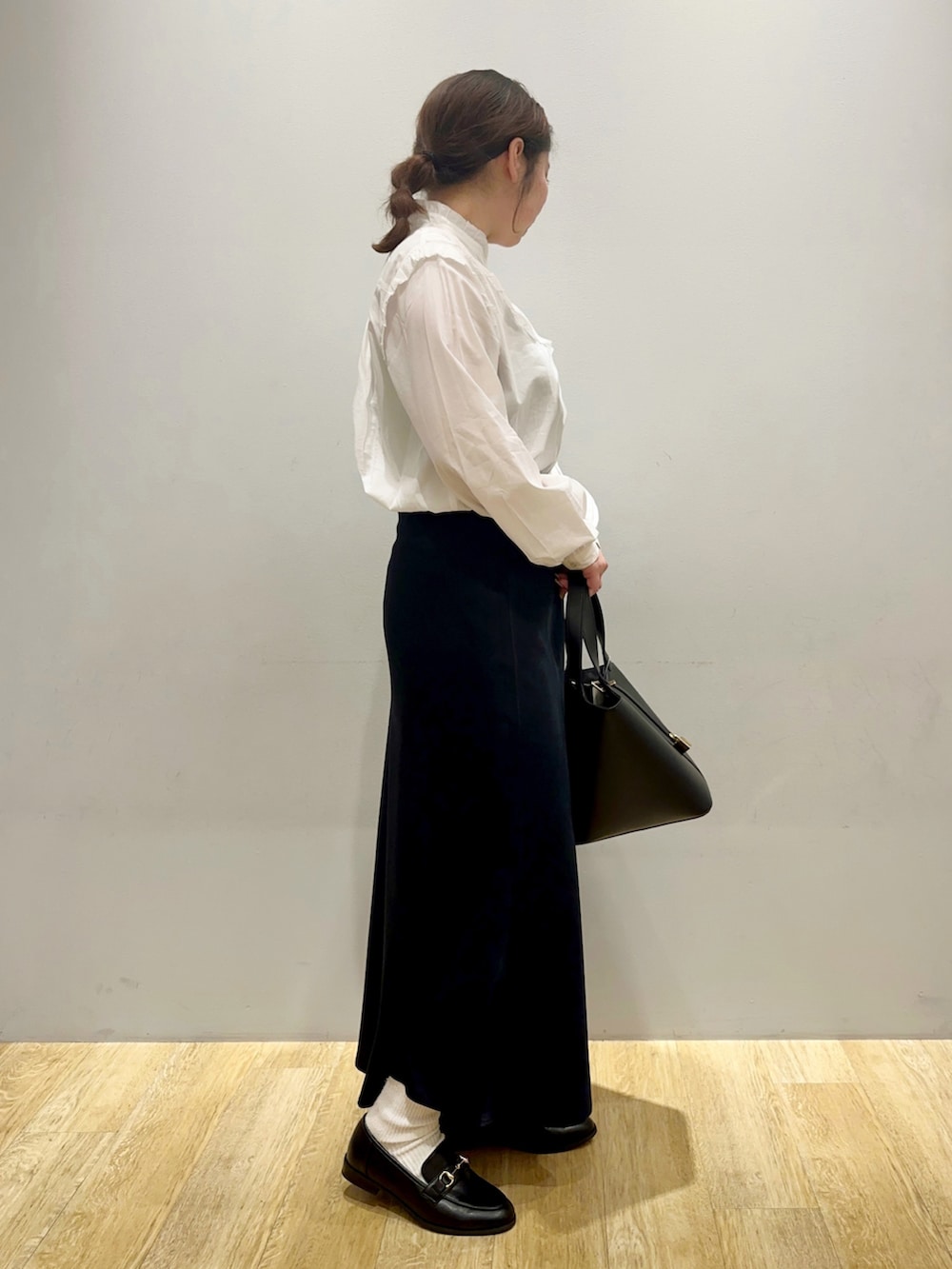 ホワイト系のシャツ/ブラウス、ブラウン系のスカート、ブラック系のエコバッグ/サブバッグを着用したレディースの冬コーディネートの2枚目の写真