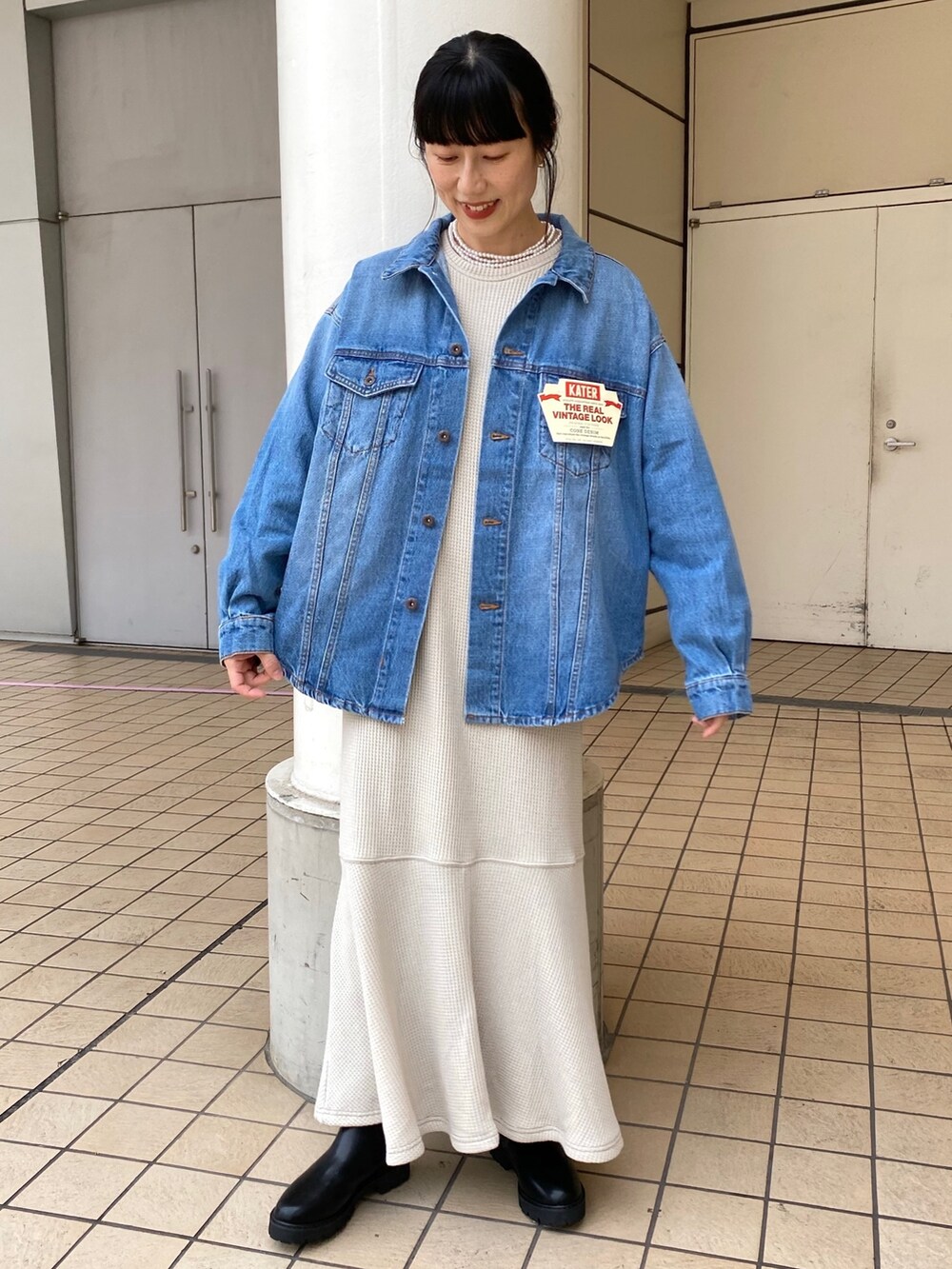 ブルー系のデニムジャケット、グレー系のワンピース、ブラック系のブーツを着用したレディースの秋コーディネートの2枚目の写真