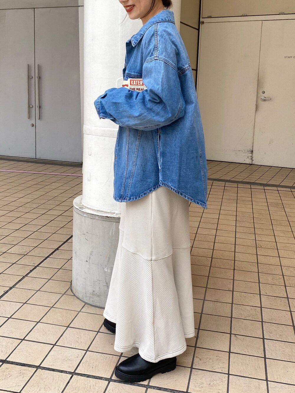 ブルー系のデニムジャケット、グレー系のワンピース、ブラック系のブーツを着用したレディースの秋コーディネートの3枚目の写真