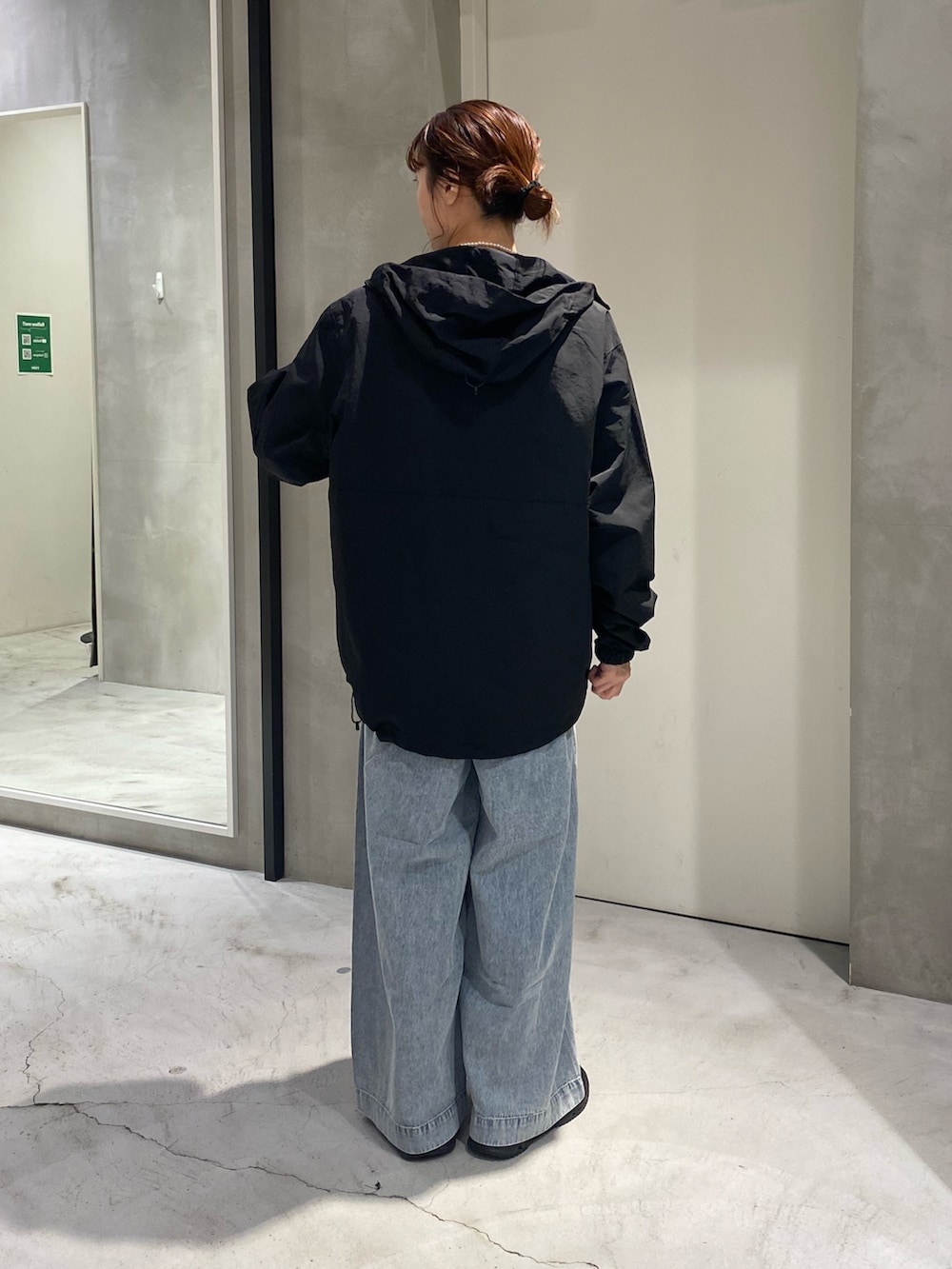 ブルー系のスウェット、ブラック系のマウンテンパーカー、ブルー系のデニムパンツを着用したレディースの秋コーディネートの3枚目の写真