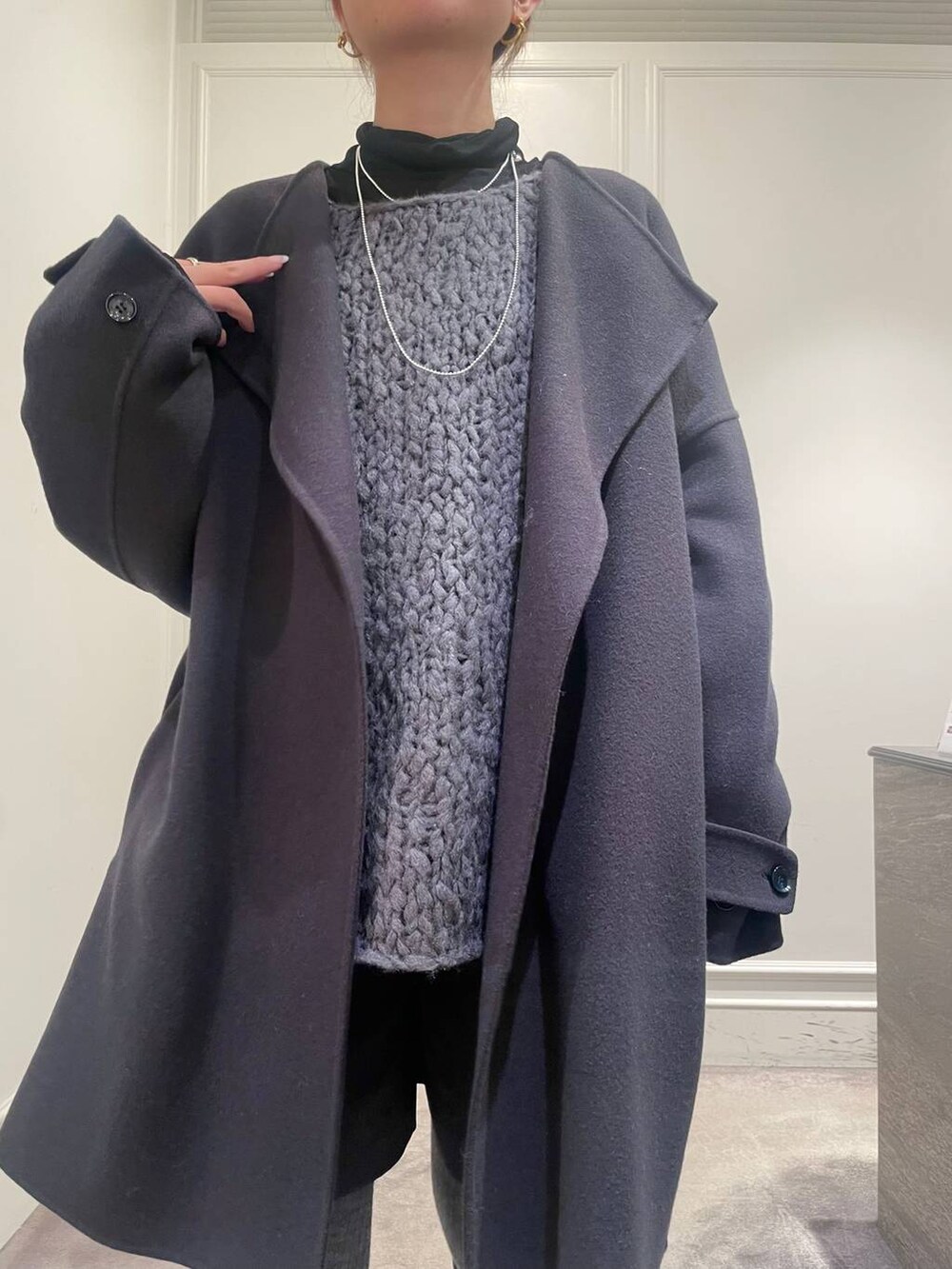 グレー系のピーコート、ブラック系のTシャツ/カットソー、グレー系のニット/セーターを着用したレディースの冬コーディネートの6枚目の写真