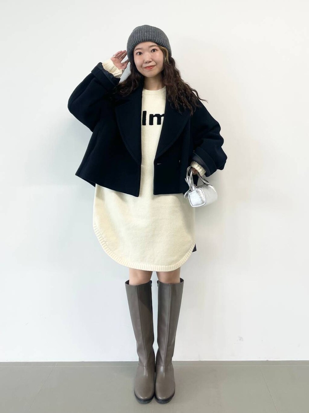 シルバー系のショルダーバッグ、ブラック系のピーコート、ホワイト系のワンピースを着用したレディースの冬コーディネートの6枚目の写真