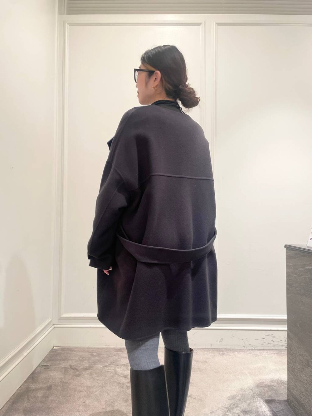 グレー系のピーコート、ブラック系のTシャツ/カットソー、グレー系のニット/セーターを着用したレディースの冬コーディネートの7枚目の写真